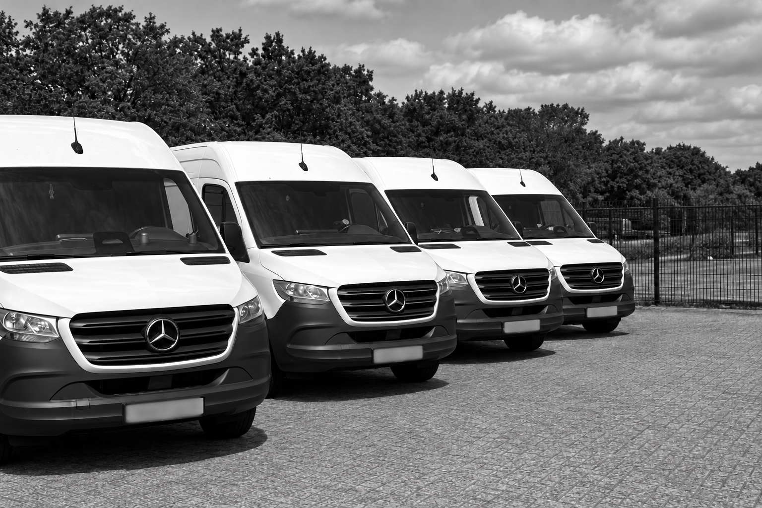 Vier witte Mercedes-bestelbussen van AT Parcel & Transport met onleesbare kentekens